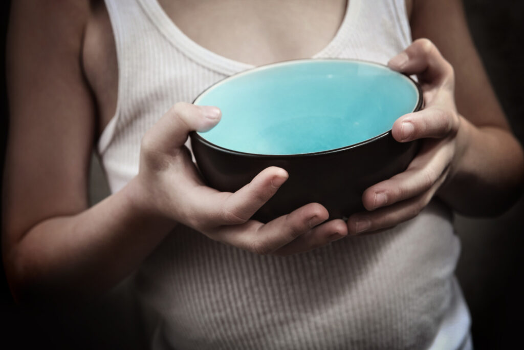 Child's hands holding an empty bowl.  Hunger